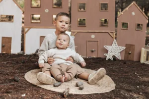 Hermanos en sesión de fotos de Navidad en exterior en Barcelona, con decorado navideño en la naturaleza