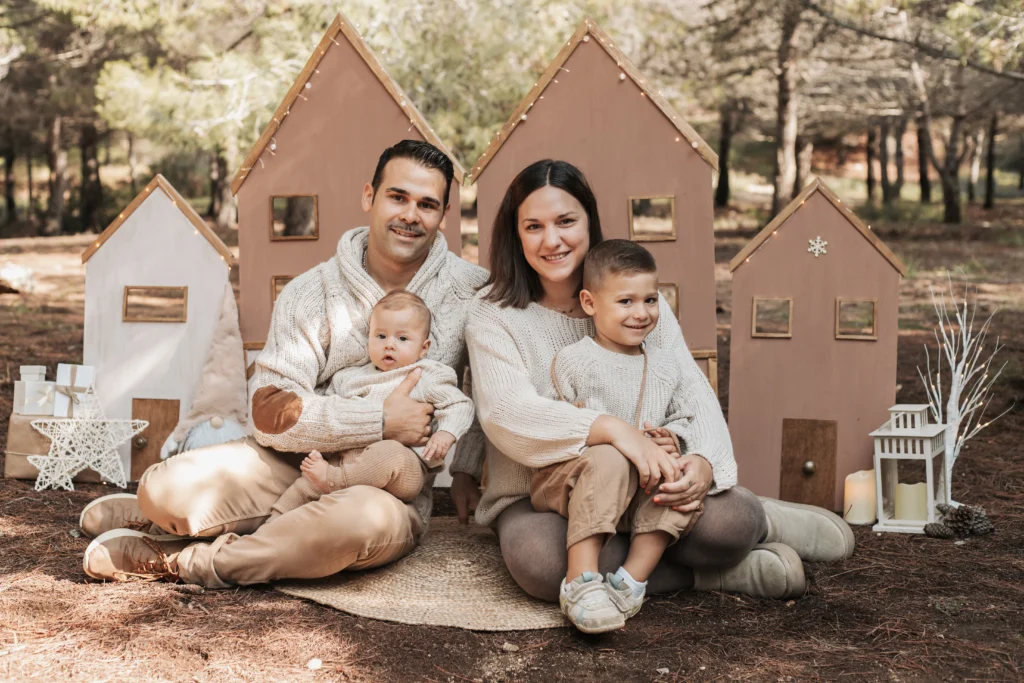 Sesión familiar de Navidad en exterior en Barcelona, padres con sus hijos en decorado navideño en la naturaleza